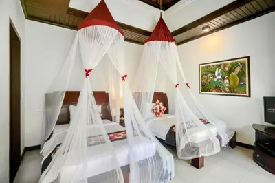 two beds in a bedroom with mosquito nets at Catra 3 BR Private Pool Villa in Seminyak