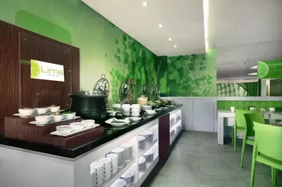 a restaurant with green walls and a counter with dishes at favehotel Sunset Seminyak in Seminyak