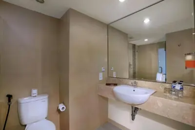 a bathroom with a toilet and a sink and a mirror at favehotel Sunset Seminyak in Seminyak