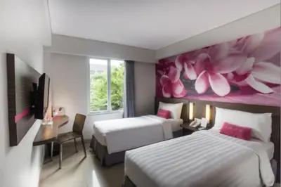 a hotel room with two beds and a painting of flowers at favehotel Sunset Seminyak in Seminyak