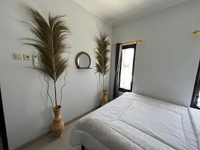 a bedroom with a bed and two plants in vases at Chandra's house in Pesanggaran
