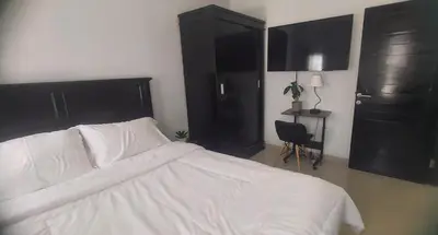 a bedroom with a white bed and black cabinets at Chandra's house in Pesanggaran
