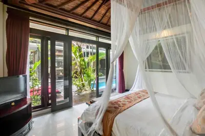a bedroom with a bed and a tv and windows at Kastara 4 BR Private Pool Villa in Seminyak