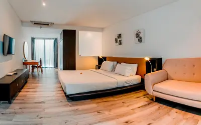 a hotel room with a bed and a couch at Sunrise Suite Seminyak by ARM Hospitality in Kerobokan