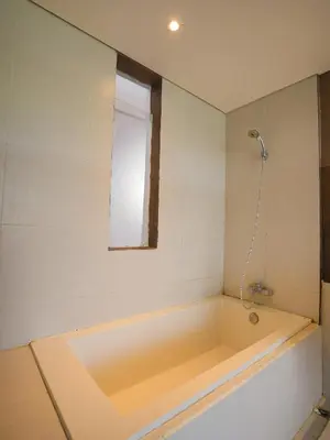 a bath tub in a bathroom with a window at Sunrise Suite Seminyak by ARM Hospitality in Kerobokan