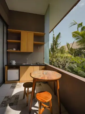 a small kitchen with a table and two stools at Sunrise Suite Seminyak by ARM Hospitality in Kerobokan