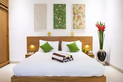 a bedroom with a large white bed with green accents at Villa Angela in Seminyak
