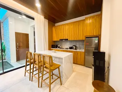 a kitchen with wooden cabinets and a counter with chairs at Villa Prada II 3BR Villa Near to Beach in Seminyak in Seminyak