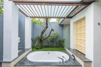 a bath tub in a bathroom with a tree at Kings Villas Sanur by Moria in Denpasar