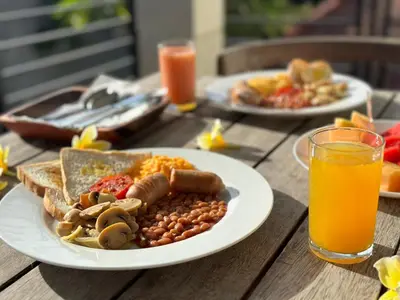 two plates of food on a wooden table with orange juice at Kings Villas Sanur by Moria in Denpasar