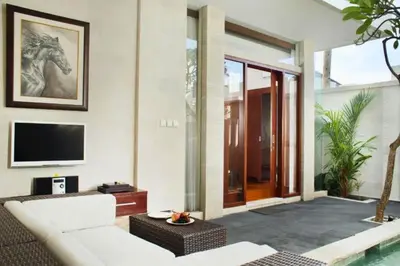 a living room with a white couch and a tv at Vadjar 1 BR Private Pool Villa in Seminyak