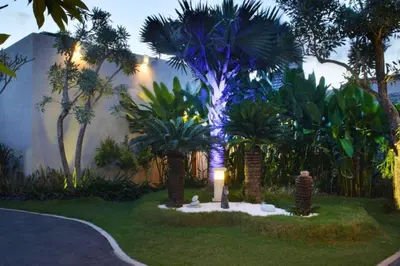 a garden with a palm tree with a blue light at Vadjar 1 BR Private Pool Villa in Seminyak