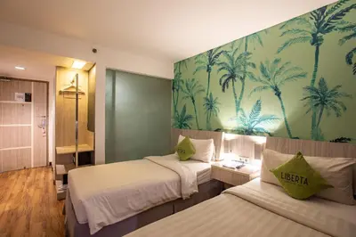 a hotel room with two beds and a mural of palm trees at Liberta Seminyak Hotel in Seminyak