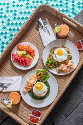 a tray with plates of breakfast food on a table at Liberta Seminyak Hotel in Seminyak
