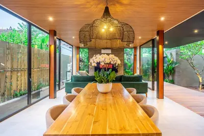 a dining room with a wooden table with flowers on it at The Continental Modern Luxury 4 BR Villa in Seminyak Central in Seminyak