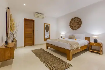 a bedroom with a bed and a table and a television at Villa Lima - 5 bdrs, BBQ, Living room with Ac and private pool in Seminyak