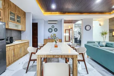 a kitchen and living room with a table and a blue couch at Villa Rumpi Seminyak by Nagisa Bali in Legian
