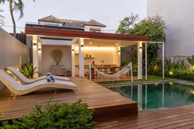 a deck with a hammock next to a swimming pool at Stylish Tropical Villa 2 Br , Canggu , 400m To Finn Beach in Canggu