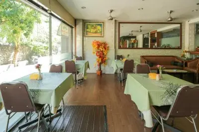 a restaurant with green tables and chairs and a mirror at Tuban Torres Accommodation in Kuta