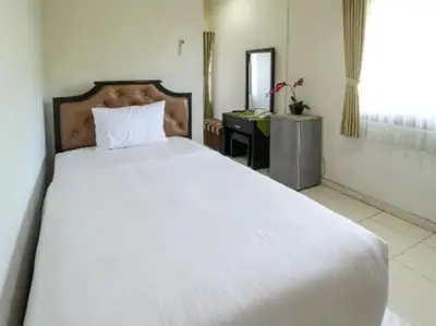 a large white bed in a room with a desk at Tuban Torres Accommodation in Kuta