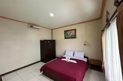 a bedroom with a bed with a red blanket at Taxa Raya Guest House in Legian