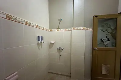 a bathroom with a shower with a glass door at Taxa Raya Guest House in Legian