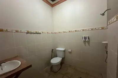 a bathroom with a toilet and a sink at Taxa Raya Guest House in Legian