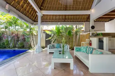 a patio with a couch and a table and a pool at Villa Bliss a Paradise of Three Independent Villas in Canggu