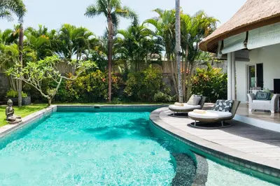 a swimming pool with two chairs and a house at Villa Bliss a Paradise of Three Independent Villas in Canggu