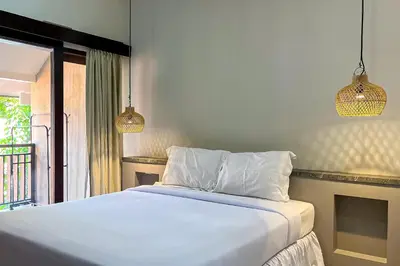 a bedroom with a white bed and two pendant lights at Sekeca Coliving in Kuta