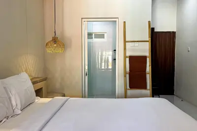 a bedroom with a white bed and a sliding glass door at Sekeca Coliving in Kuta