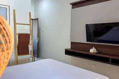 a room with a tv and a bed and a chair at Sekeca Coliving in Kuta