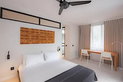 a bedroom with a bed and a desk in it at The Drupadi Apartments Town House LOLA in Seminyak