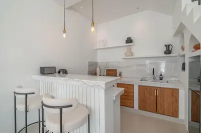 a kitchen with a counter and two stools at Villa Golden Canggu - Modern Chic 2BR Villa Near Finns Recreation Club in Canggu