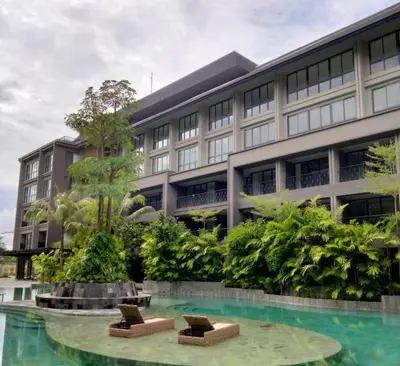 a building with two chairs in front of a pool at Lavaya Resort Nusa Dua Bali in Nusa Dua