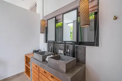 a bathroom with two sinks and two mirrors at Villa Vida Mira - Elegant 4BR Beachside Villa in Canggu in Canggu