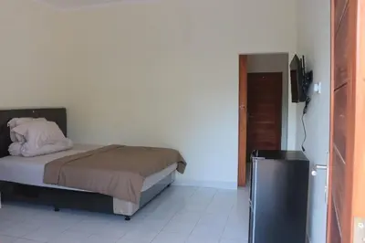 a bedroom with a bed and a television in it at Griya Mozaik in Jimbaran