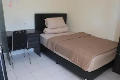 a bed with a pillow and a dresser in a bedroom at Griya Mozaik in Jimbaran
