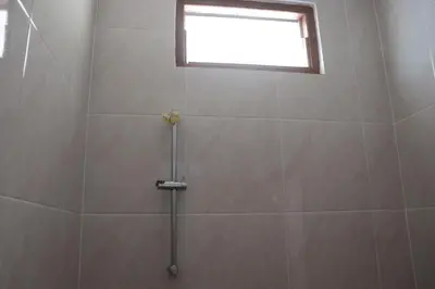 a shower stall with a window in a bathroom at Griya Mozaik in Jimbaran