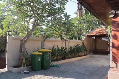 two green trash cans sitting next to a fence at Griya Mozaik in Jimbaran