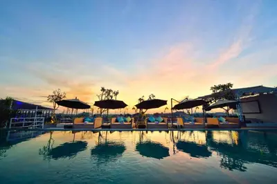 a swimming pool with umbrellas and chairs and the sunset at Antariksha 1 BR Superior Room in Seminyak