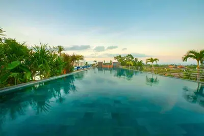 a large swimming pool at a resort with palm trees at Viorel 1 BR Whirlpool Suite Room in Seminyak