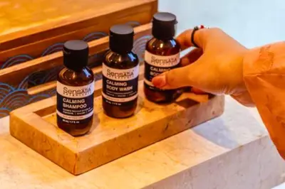 a person holding three bottles of alcohol on a wooden tray at Luxury 2 BR Villa with Private Pool & Bathtub in Seminyak