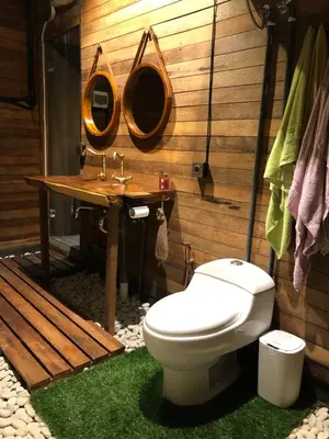 a bathroom with a toilet and two mirrors on the wall at Villa Divna in Nusa Dua