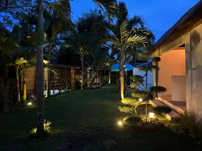a yard with palm trees and lights at night at Villa Divna in Nusa Dua