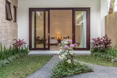 a house with glass doors and flowers in the yard at Gajah Villas Bali by Nagisa Bali in Seminyak