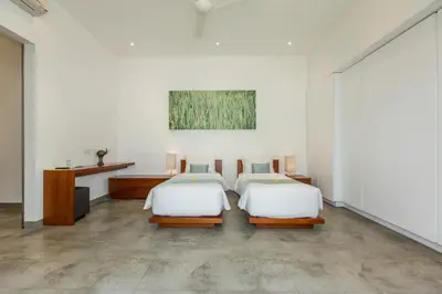 a bedroom with two beds and a desk and a painting at Gajah Villas Bali by Nagisa Bali in Seminyak
