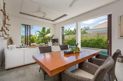 a kitchen and dining room with a wooden table and chairs at Gajah Villas Bali by Nagisa Bali in Seminyak