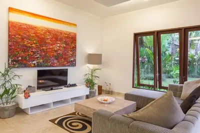 a living room with a large painting on the wall at Villa Club Corner Residence by Nagisa Bali in Canggu