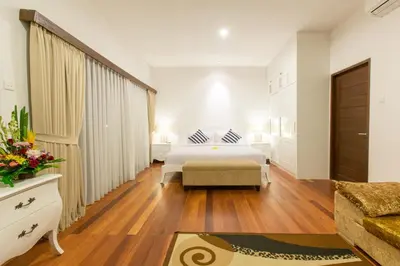 a white bedroom with a bed and a couch at Villa Club Corner Residence by Nagisa Bali in Canggu